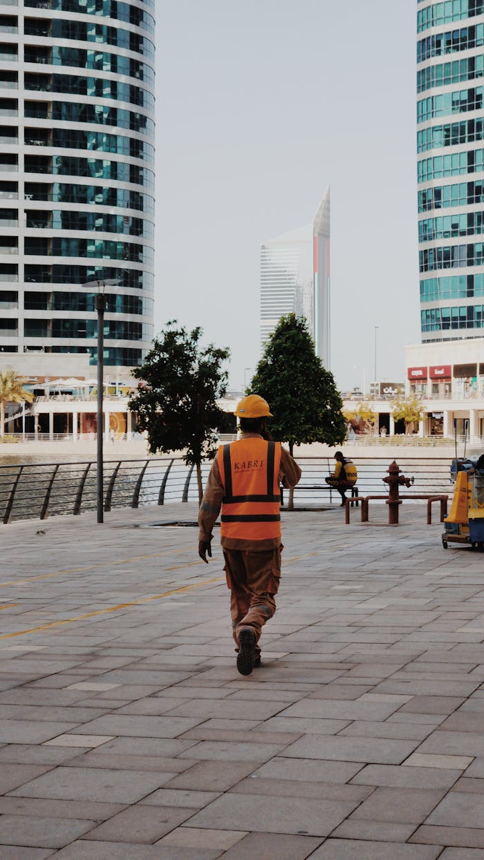 Construction worker walking in Dubai's urban landscape, showcasing modern architecture.